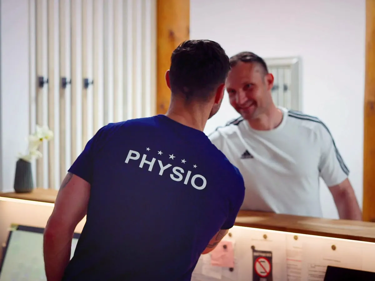 Therapeut der POM MED begrüßt einen lächelnden Patienten am Empfang der Physiotherapie im POM Weimar