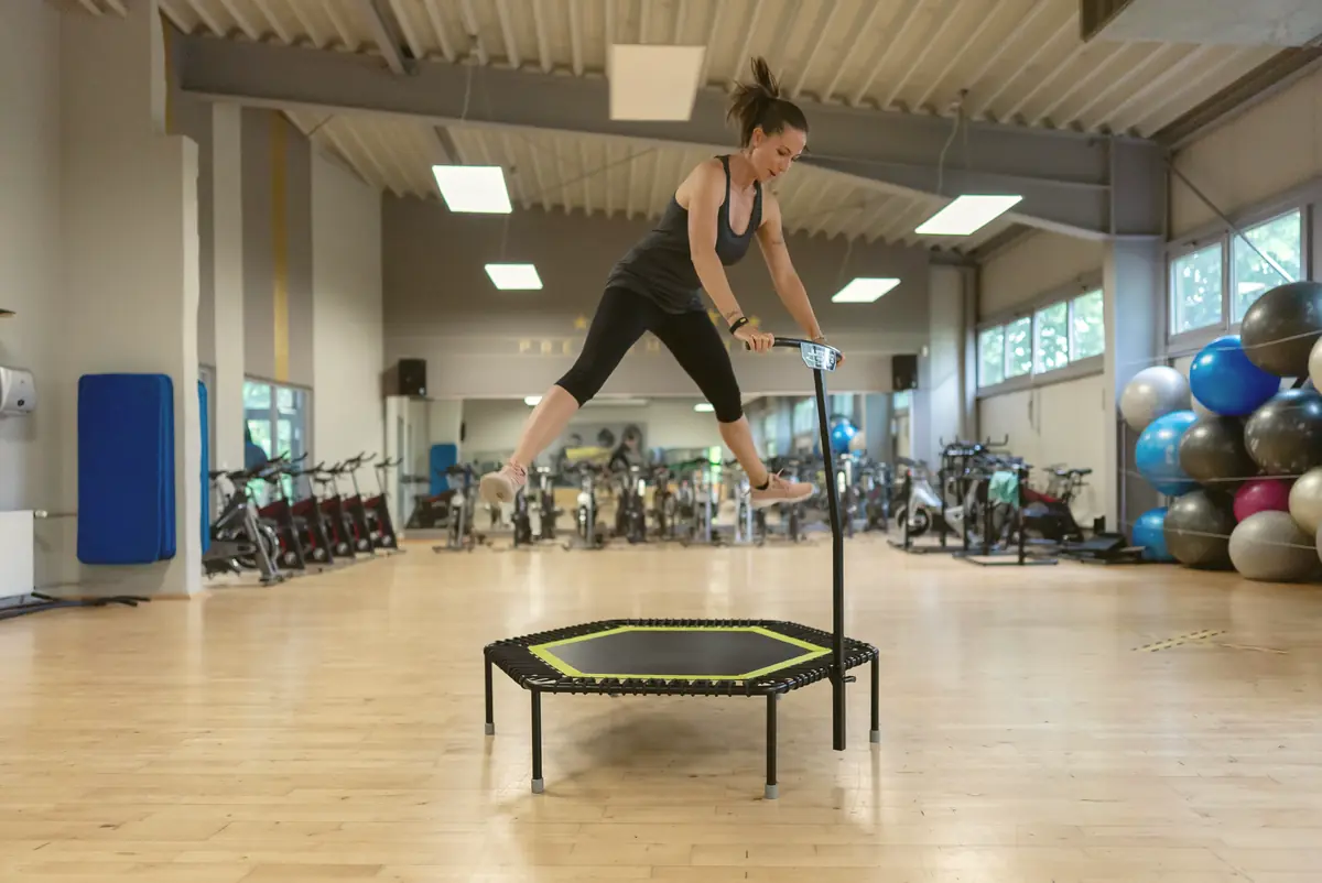 Frau beim Jumping-Fitness auf dem Trampolin im Kursraum